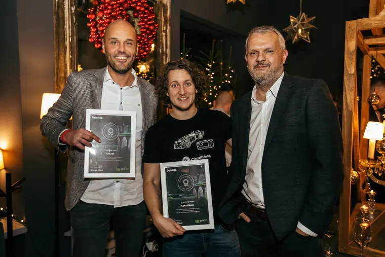 At an evening awards reception, holding a framed certificate beside two other men