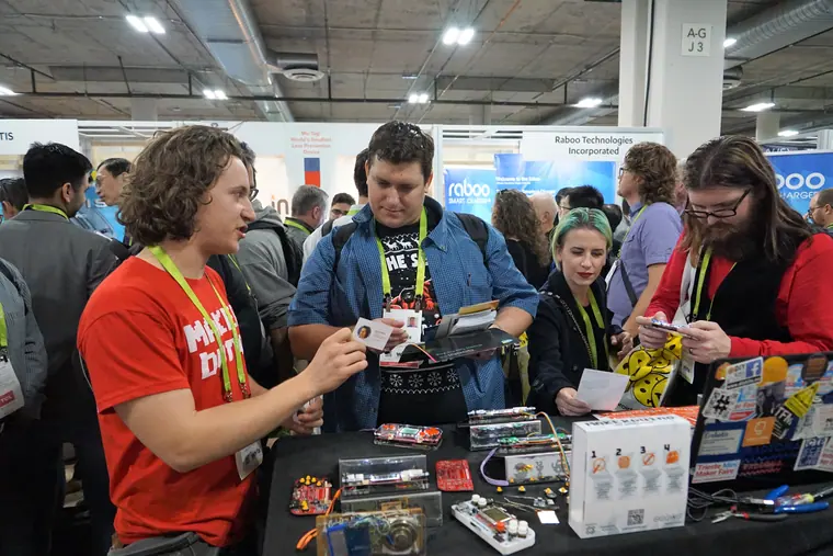Behind the stand at CES, demonstrating a console to visitors across a table of kits