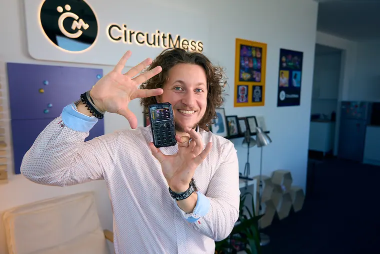 Framing the MAKERphone 2.0 beside his face with an open hand