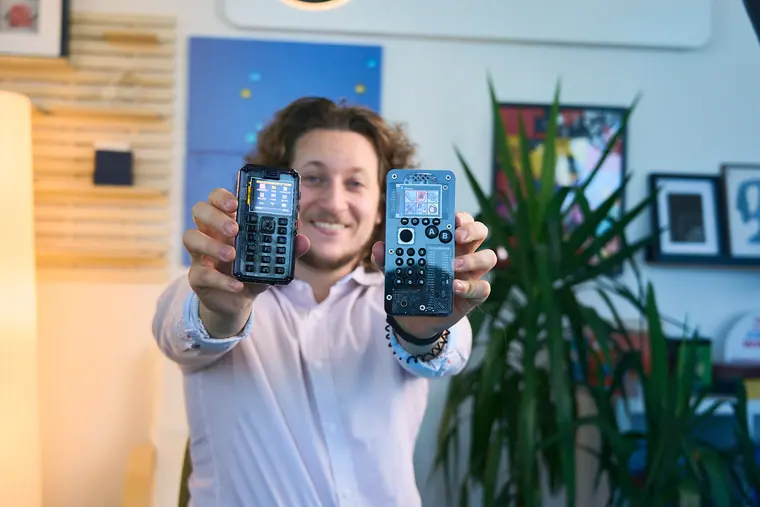 Holding up two MAKERphone 2.0 units, one in each hand, screens to camera